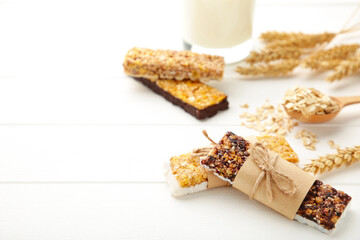 Healthy breakfast with granola bars and milk on white wooden table.