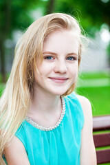 Portrait of a young blonde girl in a turquoise dress