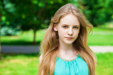 Portrait of a young blonde girl in a turquoise dress