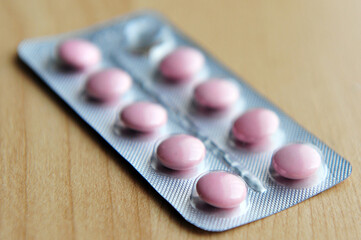 Sachet of pink pills on a wooden surface