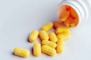 Yellow pills medication on a white surface