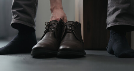 Young man put on his brown leather chukka boots indoor