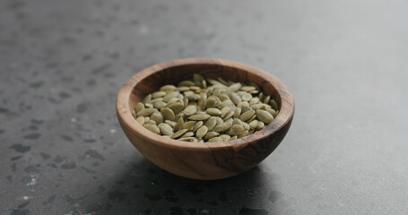 pumpkin seeds in olive bowl on terrazzo countertop with copy space