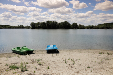 Pedalos, or paddle boats, on the shore of the Danube River, in Romania, on a sandy beach.