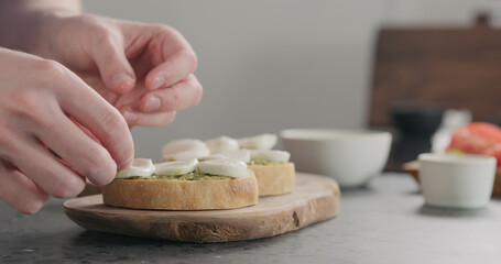 young man making bruschetta with tomato, pesto and mozzarella on olive board