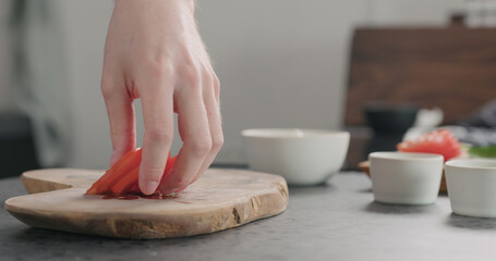 man take sliced tomato from olive wood board