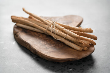 bunch of handmade wholegrain grissini tied with rope on olive board