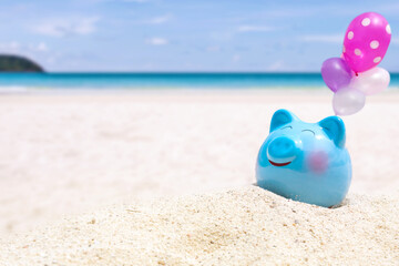 Fototapeta na wymiar Summer happy piggy bank on sand beach over blurred tropical blue sea background, image for saving vacation concept.