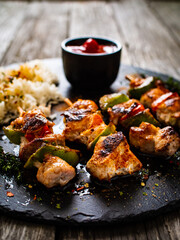 Grilled shashlik and white basmati rice on black stone plate on wooden table
