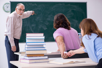 Old chemist teacher and two students in the classroom