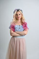 Blonde colored hair model smiling posing in studio on a white background. Vertical portrait of a pretty woman with a wreath on her head.