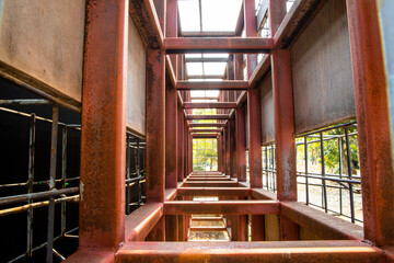 Perspective view of rusty metal structure outside a building.
