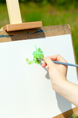 art, creativity and people concept - hand of artist with brush painting picture.