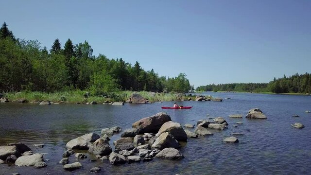 Woman and child kayaking in beautiful Nordic nature, shallow rocky waters - aerial