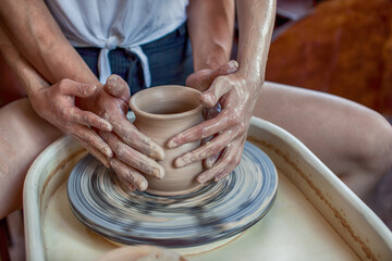 Fototapeta na wymiar Pottery. Two young men. Close-up hands working on a vase