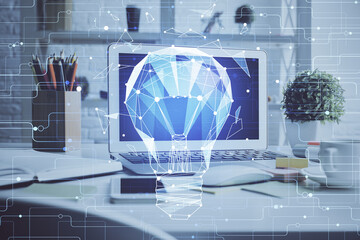 Computer on desktop in office with bulb icon hologram. Double exposure. Concept of idea.