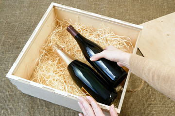 glass and bottle of expensive elite wine in a wooden box with shavings, wine tasting, online order and delivery wine in coronavirus time, internet wine shops concept