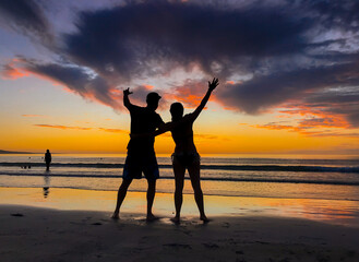 Fototapeta premium Silhouettes of couple in love at beach sunset celebrating freedom and love