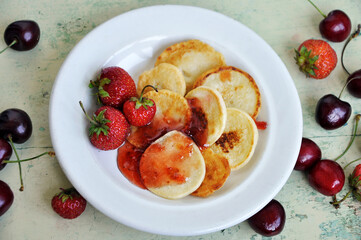 Homemade Mini pancakes and fresh strawberries, cherries on an old wooden table. Top view