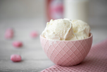 three scoops of white cream ice cream in a pink bowl