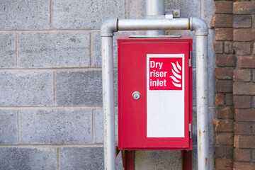 Dry riser red inlet box and sign at wall