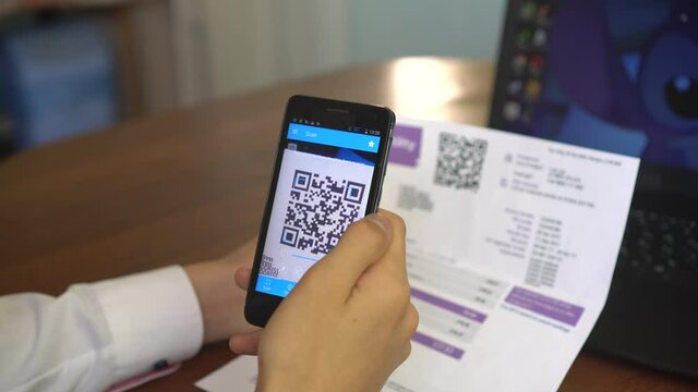 QR Utility Bill. Mobile Bill Payment with QR Codes. A woman scanning the QR code with app and paying.  A contactless payment using smartphone