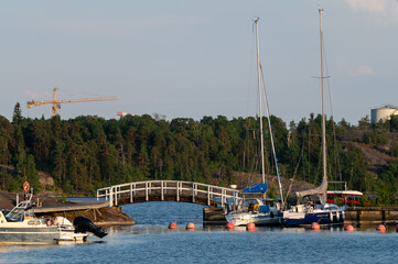 A view of a small leisure boat harbor on two separate islands connected by traditional wooden walking bridge.