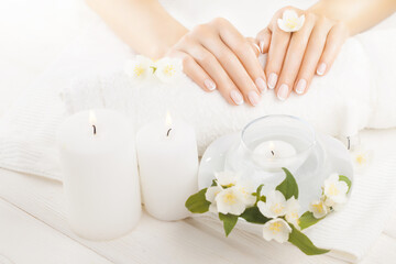 beautiful french manicure with jasmine, candle and towel on the white wooden table.