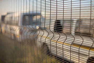 Selective focus on chainlink fence with taxis in background