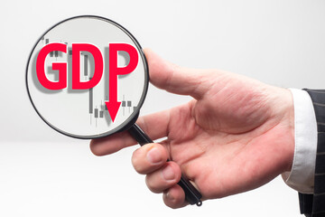 Dynamics of changes in GDP. A person looks at the GDP label and the descending chart under a magnifying glass. Deterioration of economic indicators. Economic analysis.