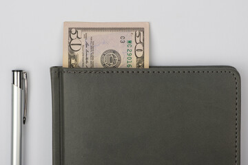 Business notebook and pen with US dollars.