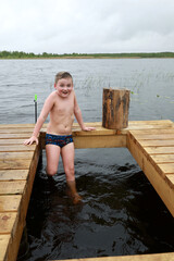 Boy sitting on wooden bridge after bath