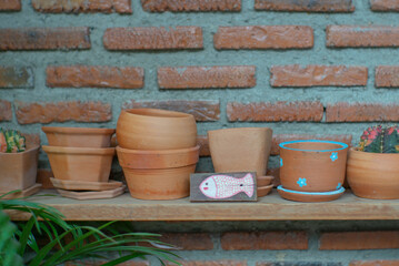 Closeup empty clay pot on the wooden shelf with blurred bricklayer wall background