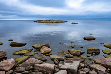Russia. Karelia. Ladoga lake. Lakes of Karelia on a background of blue sky. A small island in the lake. Stones on the shore of Lake Ladoga. Landscape of Ladoga. Traveling Untouched nature