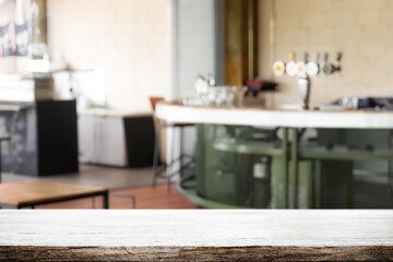 Empty wooden desk space and blurry background of pub or bar club for product display montage.