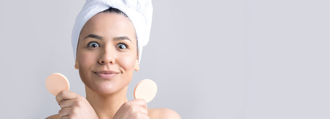 Beauty portrait of woman in white towel on head with a sponge for a body in view of a pink heart. Skincare cleansing eco organic cosmetic spa relax concept.