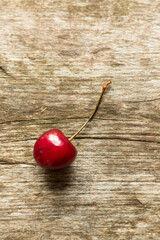 One cherry with a twig lies on an unpainted table Environmental design and minimalism