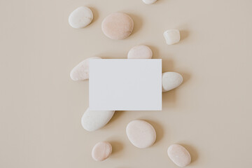 Blank paper sheet card with mockup copy space and stones on beige background. Minimal business brand template. Flat lay, top view.