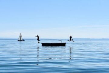 Naklejka premium Summer vacation on the lake, boat on the lake, men jumping into the water,