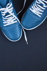Grey-blue women's leather casual shoes with white laces close-up on a black background and copy space