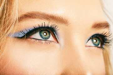 Fototapeta premium Close up image of open female blue eyes with bright makeup