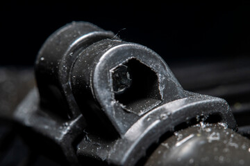 Blurred in soft focus at high magnification, the element of the connecting structure made of plastic with a screw is covered with a heel.