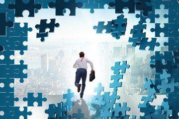 Businessman breaking the wall of jigsaw puzzle