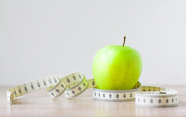 Green apple with measuring tape isolated on white background. Diet for lose weight, still life background. Healthy lifestyle concept