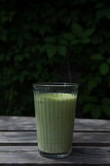 glass of matcha latte on a wooden table , side view