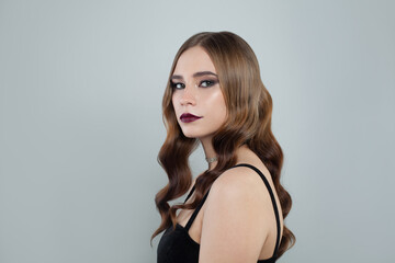 Fototapeta premium Young fashion model woman with brown curly hair and dark lipstick makeup on white