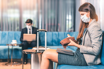 business travellers waiting for their flight at airport. beautiful business people checking airplane tickets while sitting on sofa in waiting lounge of airport. Coronavirus (COVID-19) pandemic.