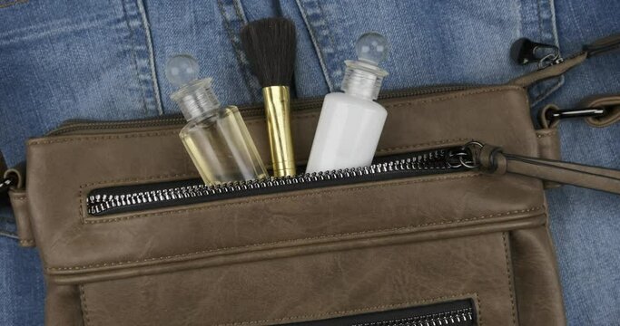 Cosmetics sticking out of the pocket of a woman's bag. Crane shot. Zoom.