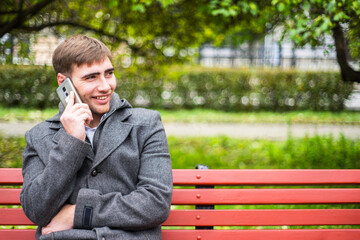 Young man sitting on the benchand talking on the smart phone