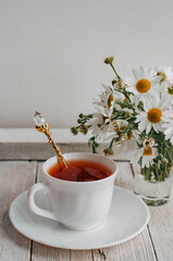 a bouquet of daisies and tea on a white wooden table